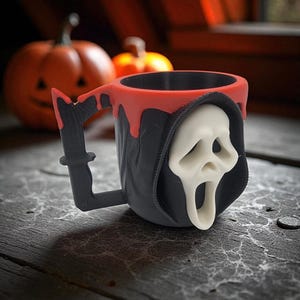Pode incluir: Caneca preta e vermelha com tema de Halloween com um design de m&aacute;scara Scream branca. A caneca tem uma borda vermelha com efeito de gotejamento, e a al&ccedil;a tem formato de faca. Ab&oacute;boras est&atilde;o no fundo.