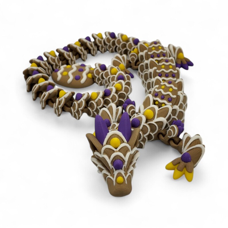 May include: A whimsical, brown dragon sculpture with intricate details. The dragon features a segmented body, adorned with white, yellow, and purple accents. The head is detailed with purple spikes and yellow orbs, creating a fantasy-themed art piece.