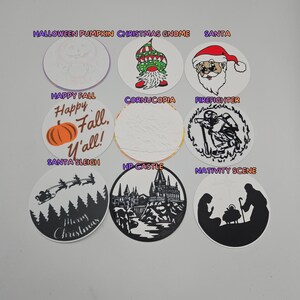 May include: A collection of circular decorative designs featuring holiday and seasonal themes. Designs include a pumpkin, gnome, Santa Claus, a fall pumpkin, a firefighter, a castle, a nativity scene, and a Santa sleigh.