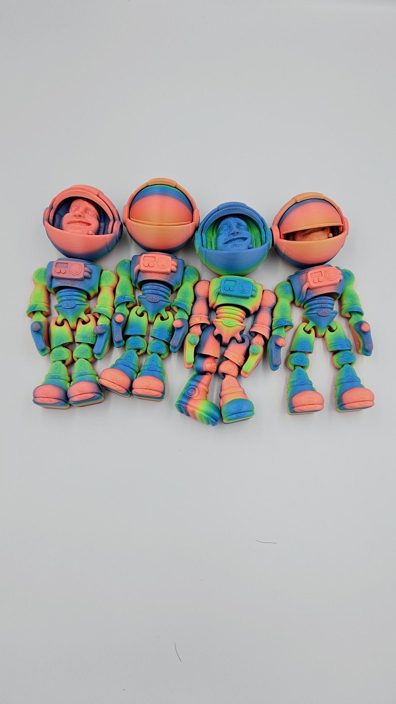 May include: Four colorful astronaut figurines with rainbow paint and articulated limbs. Each astronaut has a removable helmet with a face inside.