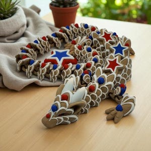 May include: A brown dragon sculpture with white, red, and blue accents. The dragon's body is made of interconnected, scale-like pieces, with star-shaped and round embellishments. The head and tail are detailed with white accents and red and blue spheres.