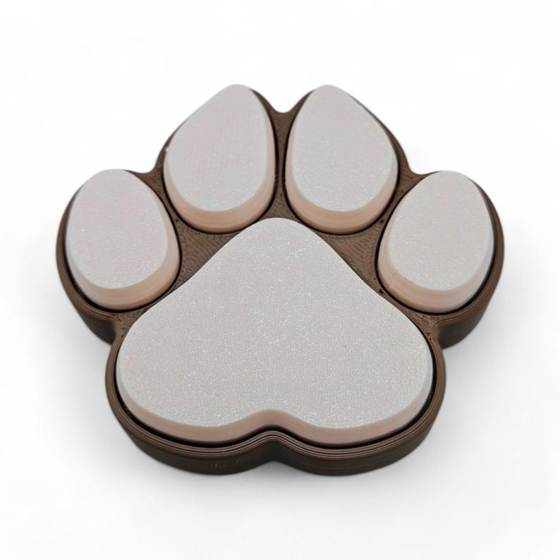 May include: A brown and white paw print-shaped object. The paw print has five white pads with a brown border. The object is likely a decorative item or a pet-themed accessory.