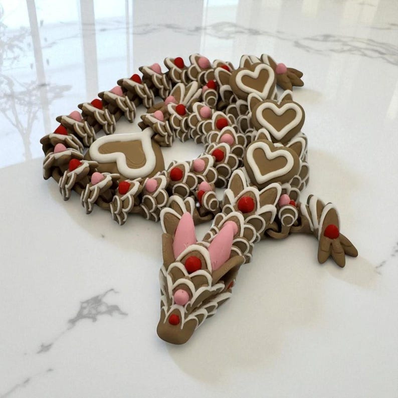 May include: A whimsical, brown dragon sculpture with heart-shaped accents and red and pink details. The dragon's body is composed of interconnected, gingerbread-like pieces, creating a unique and decorative design. The sculpture is set against a white background.