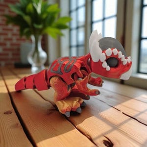 May include: A red and gray 3D-printed dinosaur figurine with a detailed design. The dinosaur has a segmented body, large feet, and a stylized head with white accents. It is posed on a wooden surface.