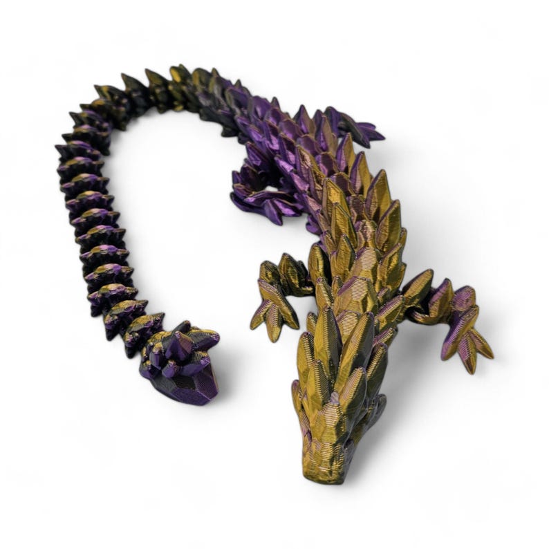 May include: A 3D printed dragon figurine with a gold and purple iridescent finish. The dragon is curled up with its tail in its mouth.