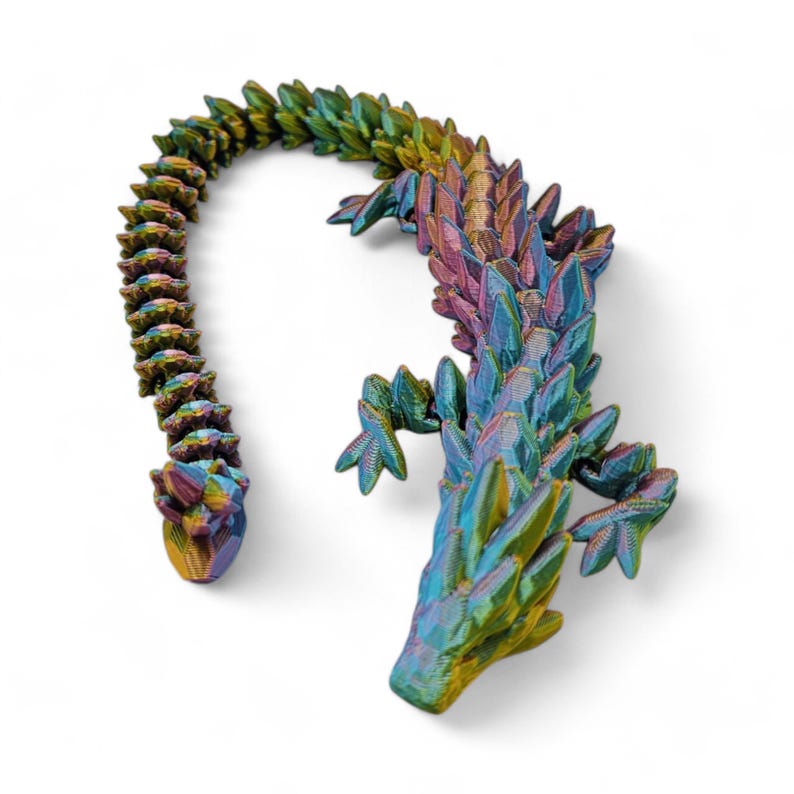 May include: A 3D printed iridescent lizard figurine with a long, segmented tail. The lizard is posed in a curled position with its head facing forward. The figurine is made of a shiny, metallic material that reflects light in a variety of colors.