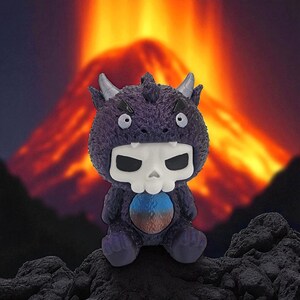 Puede incluir: Un juguete de monstruo de peluche morado con una cara en forma de calavera y peque&ntilde;os cuernos. El juguete tiene una barriga azul y marr&oacute;n y est&aacute; sentado sobre una superficie oscura y rocosa. El fondo presenta un volc&aacute;n en llamas.