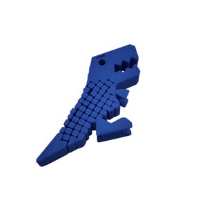 Puede incluir: Un juguete de rompecabezas azul con forma de dinosaurio. El juguete est&aacute; hecho de peque&ntilde;os bloques azules conectados, formando un Tyrannosaurus Rex. El dinosaurio tiene una cabeza detallada con dientes visibles y una cola larga.