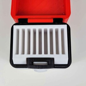 May include: A red and black storage case with a white interior. The case has multiple compartments for holding small items.