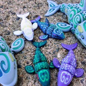 May include: A collection of six small, colorful, plastic sea creatures with a swirling pattern. The creatures are a variety of colors, including green, blue, purple, and white.