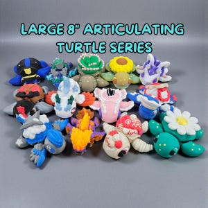 Pode incluir: Uma cole&ccedil;&atilde;o de figuras de tartarugas articuladas e coloridas, cada uma com cerca de 20 cm. As tartarugas apresentam v&aacute;rios designs, incluindo padr&otilde;es florais, geom&eacute;tricos e abstratos. O texto "LARGE 8" ARTICULATING TURTLE SERIES" &eacute; exibido no topo.
