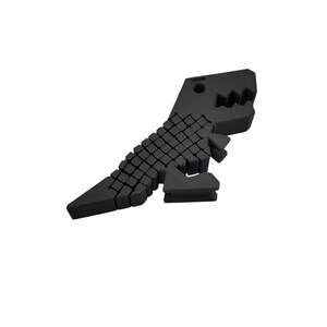 Puede incluir: Una figura de dinosaurio geom&eacute;trico negro. El dinosaurio est&aacute; construido con peque&ntilde;os bloques cuadrados, lo que le da una apariencia pixelada. La cabeza presenta una boca dentada y el cuerpo est&aacute; inclinado, sugiriendo movimiento. El dise&ntilde;o es moderno y minimalista.