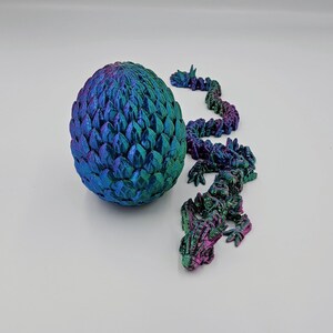 May include: A iridescent blue and green dragon egg with a matching dragon tail made of individual scales.