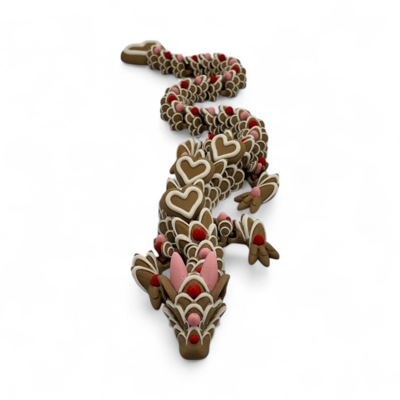 May include: A whimsical, brown gingerbread dragon with white icing details and red and pink accents. The dragon's body is segmented, with heart-shaped elements and decorative features, creating a festive and unique design.