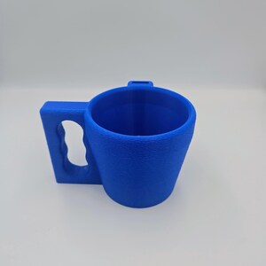 Pu&ograve; includere: Una tazza blu brillante con una superficie strutturata. La tazza presenta un'ampia maniglia rettangolare con un'impugnatura curva e una piccola linguetta sul bordo. La tazza &egrave; progettata per una facile maneggevolezza e utilizzo.