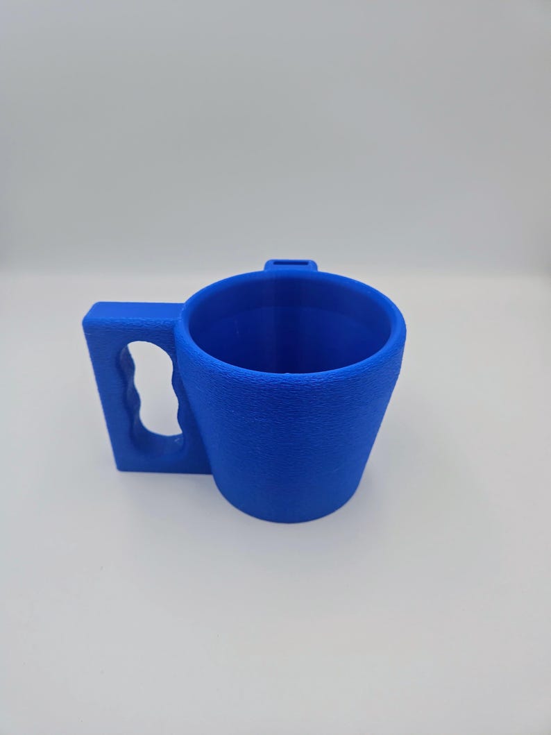 Pu&ograve; includere: Una tazza blu brillante con una superficie strutturata. La tazza presenta un'ampia maniglia rettangolare con un'impugnatura curva e una piccola linguetta sul bordo. La tazza &egrave; progettata per una facile maneggevolezza e utilizzo.