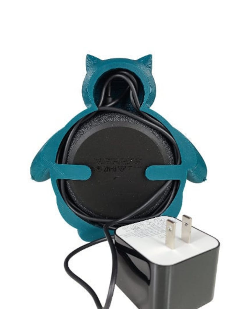 May include: A teal blue 3D printed owl-shaped holder for a smart speaker with a black power cord and a black power adapter.