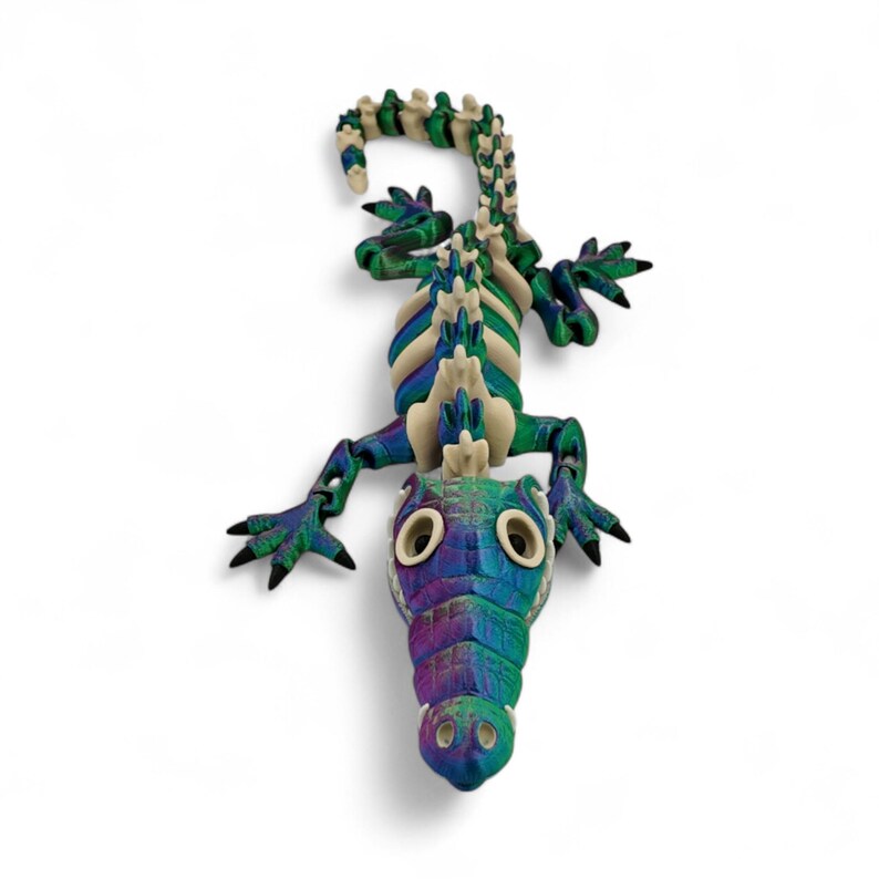 Pu&ograve; includere: Scultura di alligatore colorata con un design strutturato e dettagliato. L'alligatore presenta una vivace tavolozza di blu, verdi e viola, con una spina dorsale color crema e uno sfondo bianco. Un oggetto decorativo unico.