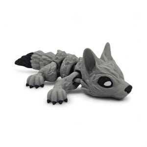 Peut inclure: Figurine de loup articul&eacute; gris avec une queue &agrave; bout noir. Le loup a une surface textur&eacute;e et d&eacute;taill&eacute;e et est pos&eacute; allong&eacute;. Les yeux sont noirs avec des reflets blancs et le nez est noir.