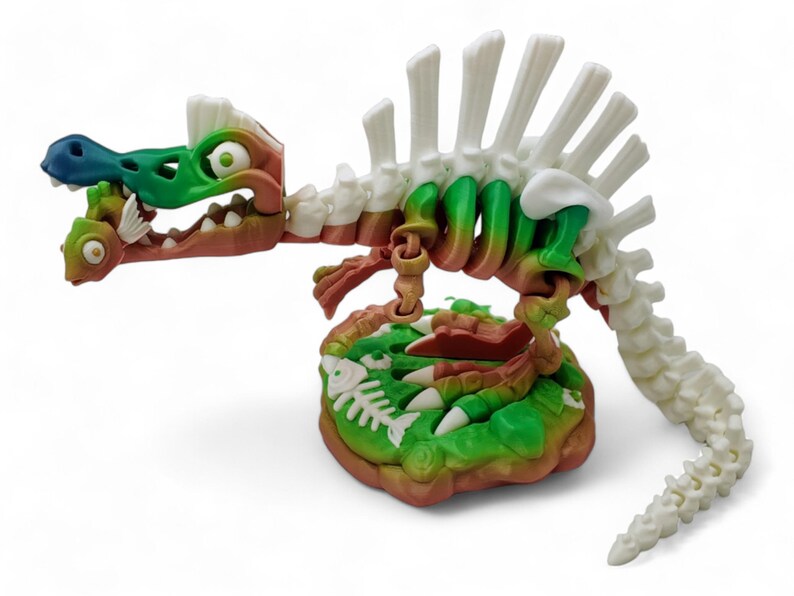 May include: A green, white, and brown plastic dinosaur skeleton toy with a fish in its mouth. The dinosaur is standing on a green and brown base with fish bones.