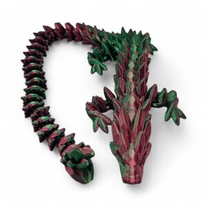 May include: A 3D printed dragon figurine with a red and green gradient color scheme. The dragon is posed with its head up and its tail curled around its body.