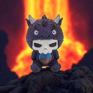 Puede incluir: Un juguete de monstruo de peluche morado con una cara en forma de calavera y cuernos peque&ntilde;os. El juguete tiene una barriga azul y marr&oacute;n y est&aacute; sentado sobre una superficie oscura y texturizada. El fondo presenta una escena ardiente naranja y roja.