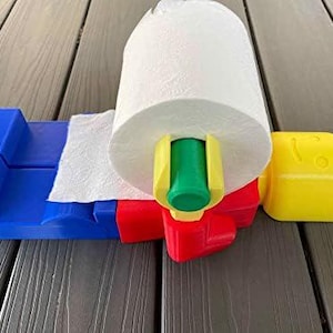 K&ouml;nnte beinhalten: Ein blau, rot, gelb und gr&uuml;n gef&auml;rbter Papierhandtuchhalter mit einer Rolle wei&szlig;er Papierhandt&uuml;cher. Der Halter hat ein gelbes, kopff&ouml;rmiges Teil an der Seite.