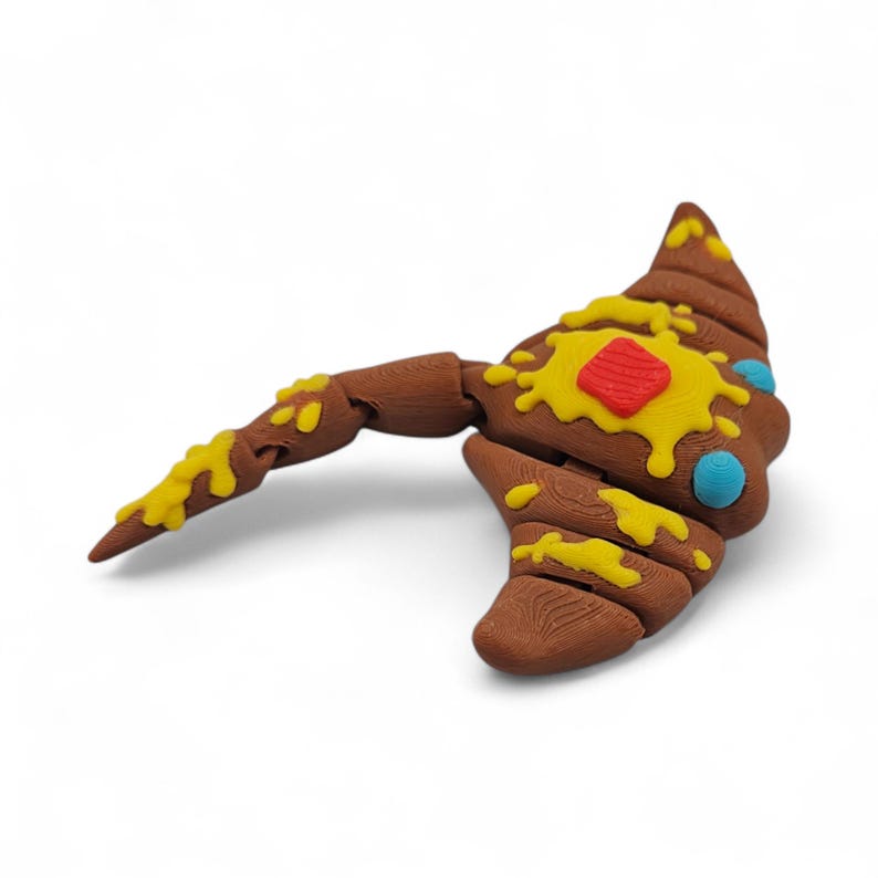 May include: A brown, stylized axe with a textured wooden appearance. The axe head features yellow and red accents, with blue and yellow details. The design is whimsical and unique.
