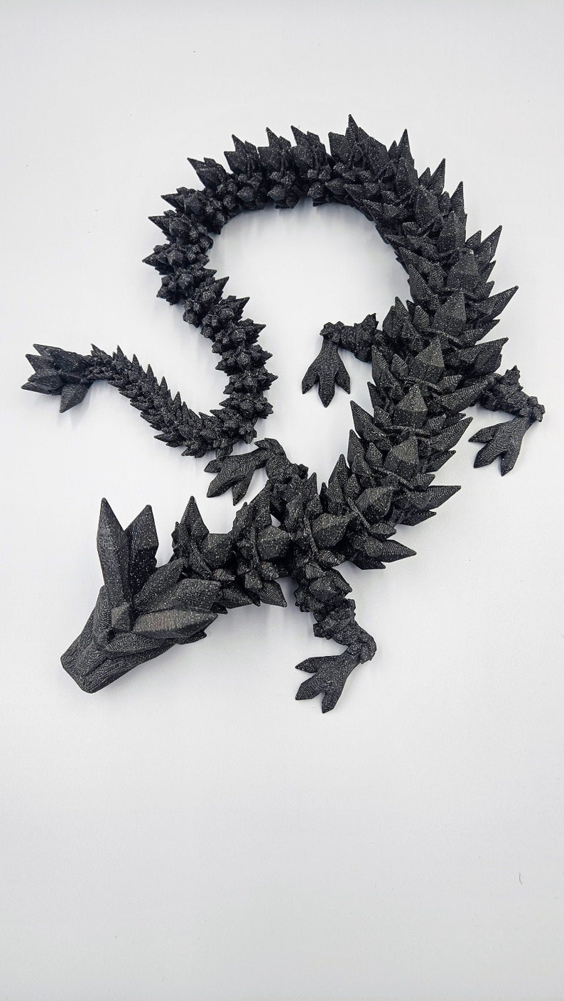 May include: A black, 3D printed dragon sculpture with a spiky, crystalline texture. The dragon is curled in a circle with its head resting on its tail.