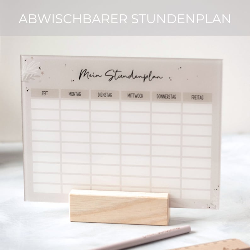 May include: A white dry-erase weekly schedule board with the text "Mein Stundenplan" at the top. The board is divided into columns for each day of the week: Monday, Tuesday, Wednesday, Thursday, and Friday. The board is on a wooden stand.