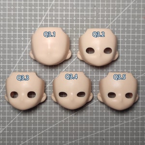 May include: Five pale pink doll heads with eye sockets and ear details are arranged on a gray grid surface. Each head is labeled with a blue text: Q3.1, Q3.2, Q3.3, Q3.4, and Q3.5. The heads are smooth and featureless.