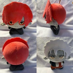 Pu&ograve; includere: Bambola di peluche con capelli rossi e un abito nero. La bambola ha un'espressione severa ed &egrave; seduta. I capelli della bambola sono acconciati a spillo. La pelle della bambola &egrave; grigia e ha gli occhi gialli.