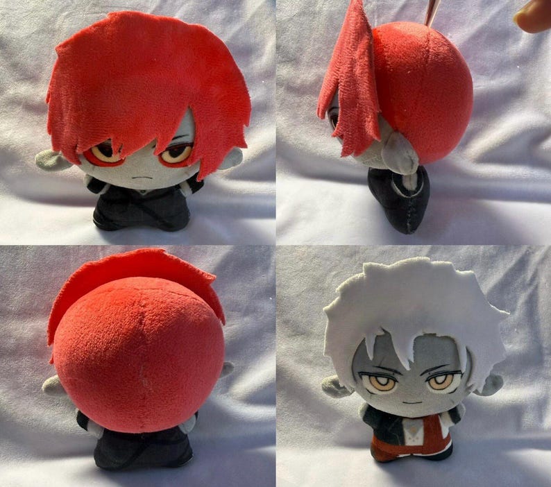 Pu&ograve; includere: Bambola di peluche con capelli rossi e un abito nero. La bambola ha un'espressione severa ed &egrave; seduta. I capelli della bambola sono acconciati a spillo. La pelle della bambola &egrave; grigia e ha gli occhi gialli.