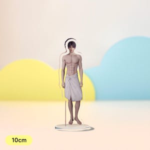 May include: A clear acrylic stand with a 10cm tall figure of a person standing with a white towel wrapped around their waist. The figure has short dark hair and a muscular build.