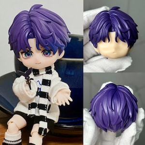 May include: A purple haired doll with a white and black striped scarf. The doll is holding a small butterfly-shaped object. The doll's head is also shown separately.