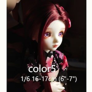 Puede incluir: Una mu&ntilde;eca a escala 1/6 con cabello largo rojo oscuro y ojos morados. La mu&ntilde;eca lleva un kimono negro y rosa con estampado floral. La mu&ntilde;eca mide 16-17 cm de alto (6-7 pulgadas).