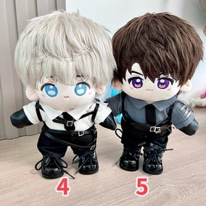 K&ouml;nnte beinhalten: Zwei Pl&uuml;schpuppen mit gro&szlig;en K&ouml;pfen und Augen im Anime-Stil. Eine Puppe hat silbernes Haar und tr&auml;gt ein wei&szlig;es Hemd, eine schwarze Hose und Stiefel. Die andere Puppe hat braunes Haar und tr&auml;gt ein graues Hemd, eine schwarze Hose und Stiefel. Beide Puppen haben schwarze G&uuml;rtel und die Zahlen 4 und 5 sind sichtbar.