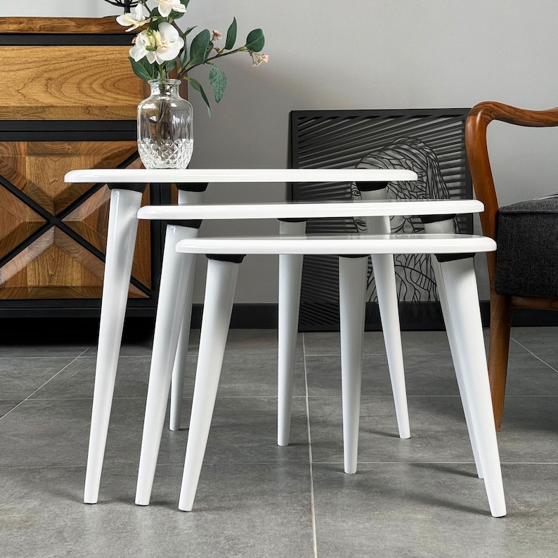 Puede incluir: Tres mesas nido blancas con un dise&ntilde;o moderno. Las mesas est&aacute;n hechas de madera y tienen un acabado blanco liso.