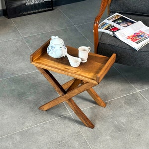 The wooden side table is seen from the top. You may see the walnut texture on the table top. The side table is placed beside the chair.