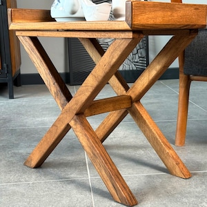 The X shape of the legs support the base of the side table. There is a connection piece at the center of the end table.