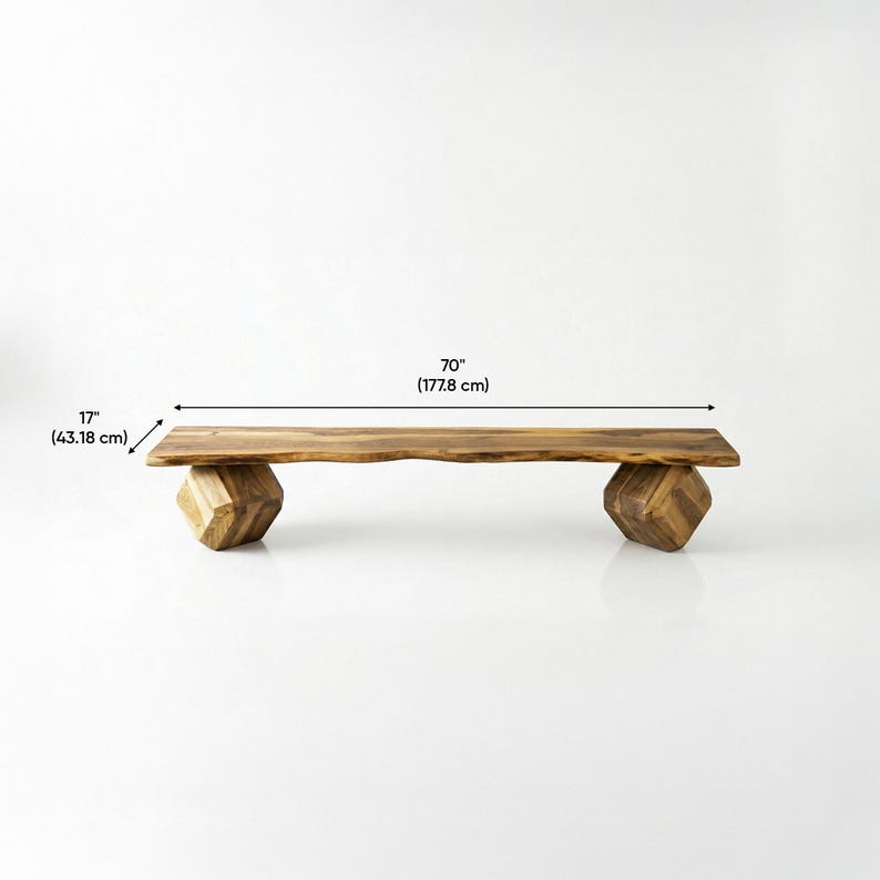 May include: A wooden bench with a natural live edge top and two geometric, faceted block legs. The bench measures 70 inches in length and 17 inches in width, featuring a warm brown wood grain pattern throughout the entire structure.