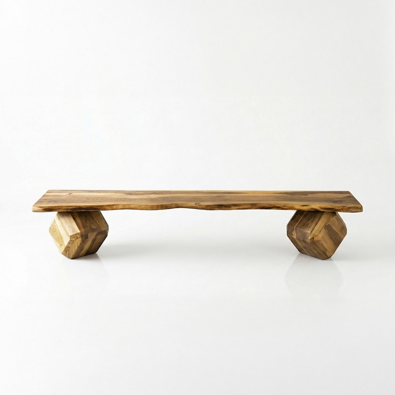 May include: A wooden bench with a natural edge top and geometric cube-shaped legs. The bench is made of light brown wood and has a minimalist design. The bench is approximately 60 inches long.