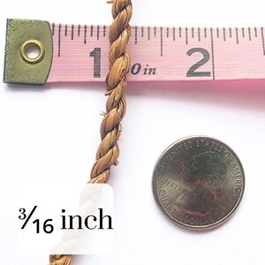 May include: Close-up of a twisted, light brown rope, measured at 3/16 inch in diameter with a pink measuring tape. A U.S. quarter coin is next to the rope for size comparison. The rope is made of natural fibers.