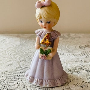 Vintage 4th Birthday Girl, A porcelain figurine of a little girl holding a small item with a rose design and a elegant gold number 4, wearing a light lavender dress.