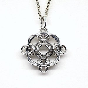 May include: A silver chain necklace with a silver pendant featuring a geometric design. The pendant is made of interwoven metal rings.