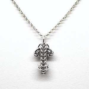 May include: A silver chain necklace with a silver pendant in the shape of a stylised cross.