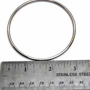 Puede incluir: Un anillo de metal plateado que mide 5 cm de diámetro. El anillo se muestra junto a una regla para referencia de tamaño.