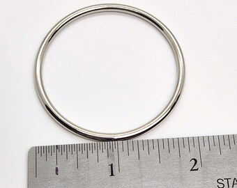 May include: A silver metal ring measuring 1 inch in diameter. The ring is shown next to a ruler for size reference.