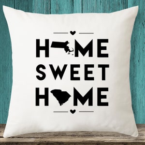 May include: White throw pillow with black text that reads "Home Sweet Home" with the outlines of the states of Massachusetts and South Carolina replacing the "O"s in the word "Home".