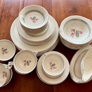 May include: A set of vintage white china dinnerware with a green and gold trim and a floral design. The set includes plates, bowls, cups, and a gravy boat.